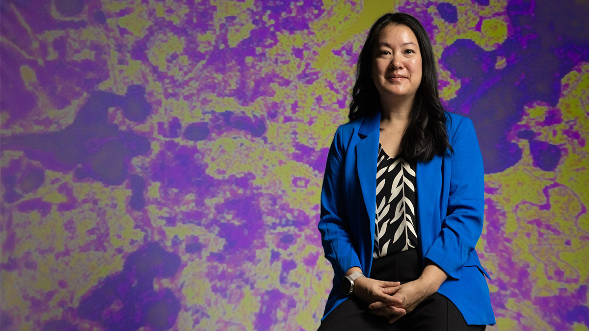 Professor Angel Hsu poses in front of purple and yellow heat map.